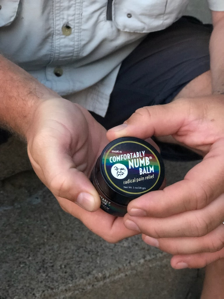 Man holding his ultra strength Comfortably Numb Balm on his steps.